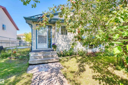 Exterior featuring light-colored siding, a covered entry, and multiple windows - 13028 34 Street Nw, Edmonton, AB 