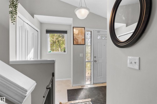 Vaulted ceiling with a flush-mount pendant light, paneled entry door with sidelights, and a window with roller blind - 13028 34 Street Nw, Edmonton, AB 