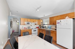 Kitchen featuring wood-finish cabinetry, white appliances, track lighting, and a window - 