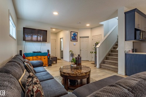 Open-concept living space with light wood-finish flooring, recessed lighting, and a window providing natural illumination - 41 Sequoia Bend, Fort Saskatchewan, AB 