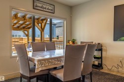 Dining area with wood-finish flooring and a large window overlooking a covered outdoor patio - 