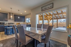 Open-concept kitchen and dining area featuring a full wall of cabinetry, a multi-pane window, and recessed lighting - 
