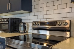 Stainless steel electric range with a smooth black cooktop, complemented by subway tile backsplash - 