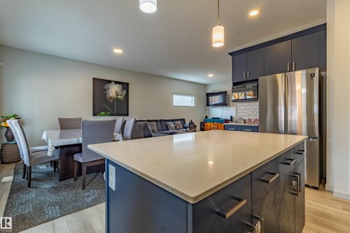 Kitchen island featuring a light-toned countertop, dark base cabinetry, and matte black hardware - 41 Sequoia Bend, Fort Saskatchewan, AB 