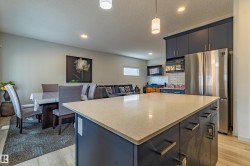 Kitchen island featuring a light-toned countertop, dark base cabinetry, and matte black hardware - 