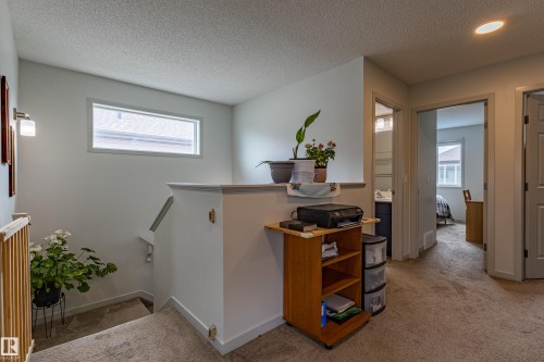 Carpeted landing featuring a half-wall railing, a rectangular window, and a wall sconce - 41 Sequoia Bend, Fort Saskatchewan, AB 