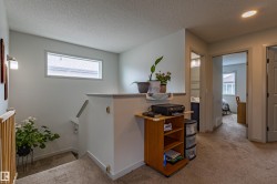 Carpeted landing featuring a half-wall railing, a rectangular window, and a wall sconce - 