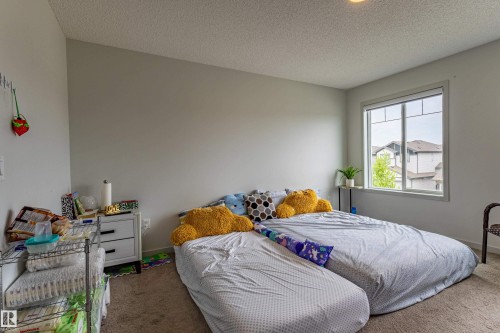 Carpeted bedroom with neutral wall tones and a window with white trim - 41 Sequoia Bend, Fort Saskatchewan, AB 