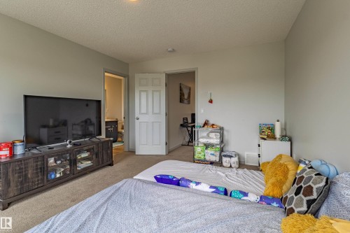 Carpeted room with light gray walls, a textured ceiling, and a white paneled door - 41 Sequoia Bend, Fort Saskatchewan, AB 