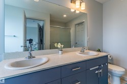 Bathroom featuring a dual vanity with a light-toned countertop, two integrated sinks, and blue cabinetry with silver-toned hardware - 