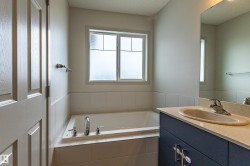 Bathroom featuring a built-in tub with chrome fixtures, a frosted window, and white tiled surround - 