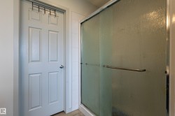 Shower enclosure featuring a framed frosted glass door with chrome hardware, complemented by a white paneled door with a spherical chrome knob - 