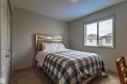 Neutral-toned bedroom featuring a textured ceiling, a window with white trim, and a bi-fold closet - 