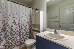 Bathroom featuring a single vanity with an oval sink and chrome faucet, a light-colored countertop, and a blue base cabinet - 
