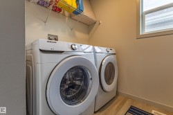 Dedicated laundry area featuring a front-load washer and dryer set, wire shelving, a window, and wood-finish flooring - 