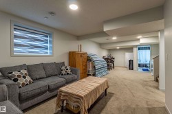 Spacious lower-level area featuring recessed lighting, a window with a patterned blind, and neutral-toned carpeting - 