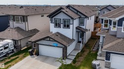 Contemporary two-story home featuring white siding with dark trim accents and a two-car garage - 