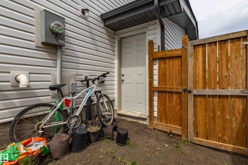 Rear exterior featuring white horizontal siding, a white service door, and a natural wood privacy fence - 41 Sequoia Bend, Fort Saskatchewan, AB 