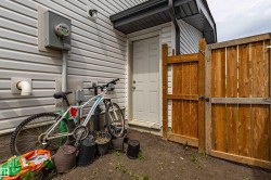 Rear exterior featuring white horizontal siding, a white service door, and a natural wood privacy fence - 
