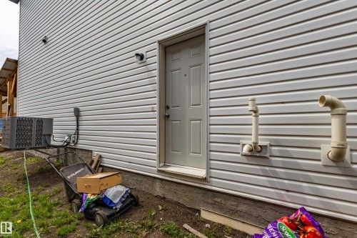 White vinyl siding exterior featuring an exterior door, an HVAC unit, and foundation - 41 Sequoia Bend, Fort Saskatchewan, AB 