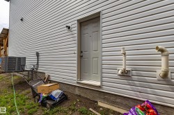 White vinyl siding exterior featuring an exterior door, an HVAC unit, and foundation - 