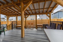 Expansive covered deck featuring wood framing, a metal roof, composite decking, and a wood privacy fence - 