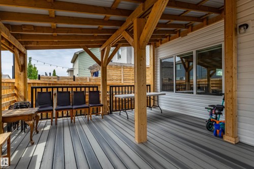 Covered outdoor deck featuring composite wood-finish flooring, a wood-framed roof with a corrugated metal ceiling, and a black metal railing - 41 Sequoia Bend, Fort Saskatchewan, AB 