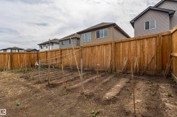 Spacious backyard with a wood privacy fence, featuring cultivated garden beds and garden stakes - 