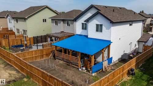 Rear exterior featuring a covered patio with a blue metal roof, white siding, and dark-framed windows - 41 Sequoia Bend, Fort Saskatchewan, AB 