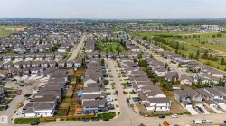Aerial perspective showcasing a residential neighborhood with diverse housing styles, paved streets, and green spaces - 