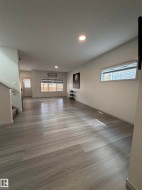 Expansive living area featuring wood-finish flooring, recessed lighting, and crisp white walls - 