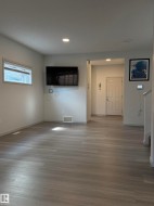Living area featuring wood-finish flooring, recessed lighting, white trim, and a rectangular window with blinds - 