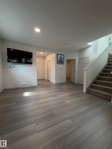 Spacious interior featuring wood-finish flooring, recessed lighting, and a carpeted staircase - 41 Sequoia Bend, Fort Saskatchewan, AB 