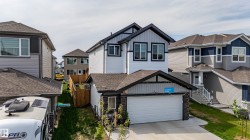 Contemporary two-story residence featuring a two-car garage, white siding, and dark trim accents - 
