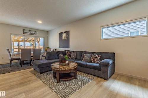 Open-concept living space with wood-finish flooring, recessed lighting, and a large dining area featuring sliding glass doors to the exterior - 41 Sequoia Bend, Fort Saskatchewan, AB 