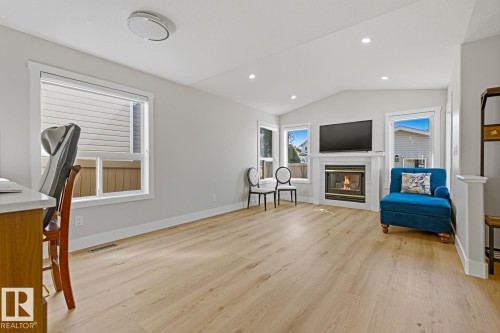 Living area with wood-finish flooring, a white mantel fireplace, multiple windows, and recessed lighting - 3830 22 Street Nw, Edmonton, AB 