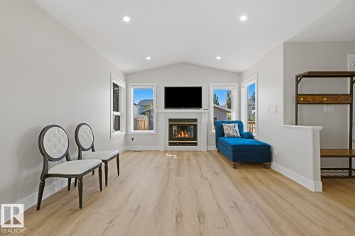 Vaulted ceiling, recessed lighting, wood-finish flooring, white trim, and a fireplace with a white mantel - 3830 22 Street Nw, Edmonton, AB 