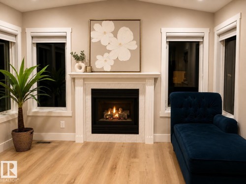 Built-in fireplace with a white mantel and tile surround, recessed lighting, wood-finish flooring, and multiple windows with trim - 3830 22 Street Nw, Edmonton, AB 