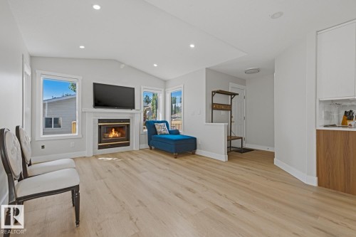 Vaulted ceiling, recessed lighting, wood-finish flooring, fireplace with white mantel, and multiple windows - 3830 22 Street Nw, Edmonton, AB 