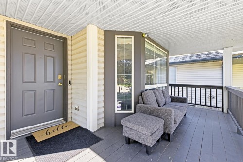Covered porch with wood-finish decking, multi-pane windows, and a panel front door - 3830 22 Street Nw, Edmonton, AB 