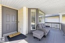 Covered porch with wood-finish decking, multi-pane windows, and a panel front door - 3830 22 Street Nw, Edmonton, AB 