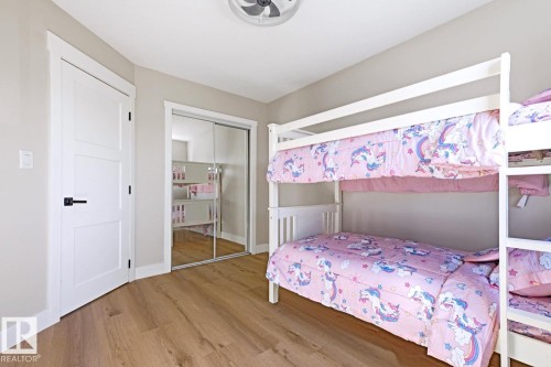 Wood-finish flooring with a white trim, a white paneled door with black hardware, and a mirrored sliding closet door - 3830 22 Street Nw, Edmonton, AB 