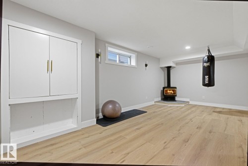 Finished space featuring wood-finish flooring, a built-in wood-burning stove with hearth, built-in cabinetry, recessed lighting, and a window - 3830 22 Street Nw, Edmonton, AB 