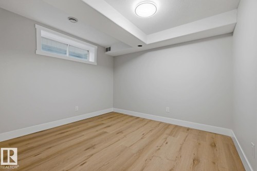 Recessed ceiling light, wood-finish flooring, egress window, neutral wall paint, and overhead lighting - 3830 22 Street Nw, Edmonton, AB 