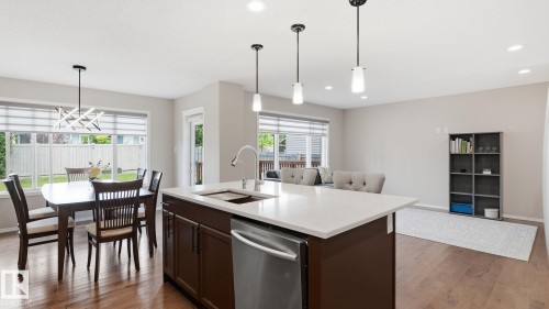 Open-concept living space with wood-finish flooring, a kitchen island featuring a stainless steel dishwasher and sink, and recessed ceiling lighting - 4610 Westcliff Point(E) Sw, Edmonton, AB 