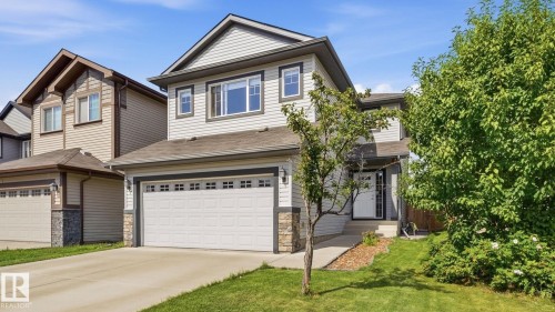 Two-story residence featuring light gray siding, dark trim accents, stone veneer detailing, an attached garage, and a concrete driveway - 4610 Westcliff Point(E) Sw, Edmonton, AB 