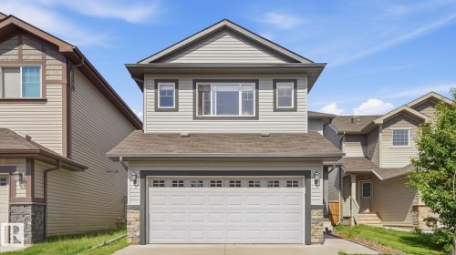 Two-story residence featuring light gray siding, a double garage with decorative windows, and dark trim details - 4610 Westcliff Point(E) Sw, Edmonton, AB 