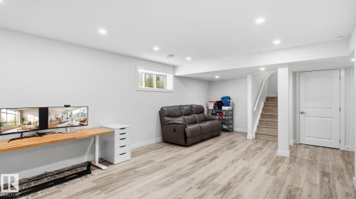 Spacious lower level featuring wood-finish flooring, recessed lighting, and a window with blinds - 4610 Westcliff Point(E) Sw, Edmonton, AB 
