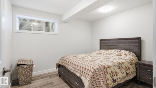 Basement bedroom featuring wood-finish flooring, a window with horizontal blinds, and a flush-mount ceiling light - 4610 Westcliff Point(E) Sw, Edmonton, AB 