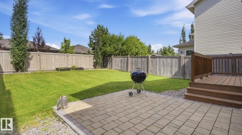 Expansive backyard featuring a manicured lawn, paver patio, wood privacy fencing, and a wood deck with railings - 4610 Westcliff Point(E) Sw, Edmonton, AB 